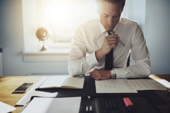 Berufswelt Consulting Training Mann brütet über Dokumenten vor sich auf dem Tisch