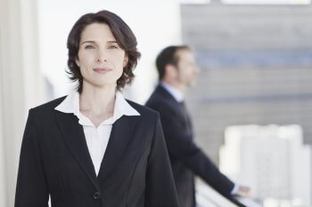 Berufsinterview HR Managerin Frau  im Anzug im Vordergrund, im Hintergrund Business-Szene