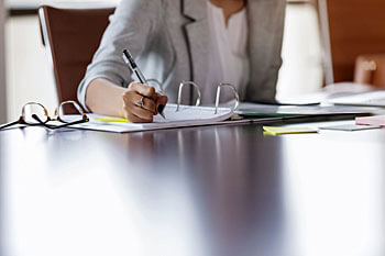 Geschäftsfrau arbeitet am Schreibtisch mit Unterlagen.