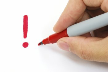 Hand mit Stift, die ein rotes Ausrufezeichen gemalt hat