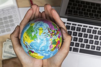 Hände, die eine kleine Weltkugel halten