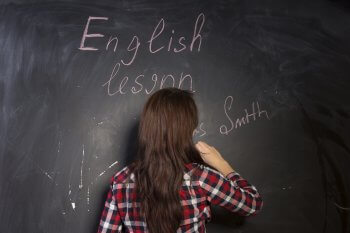Mädchen schreibt auf Tafel English Lesson