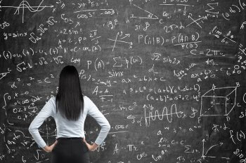 Studentin steht vor Tafel mit mathematischen Rechnungen