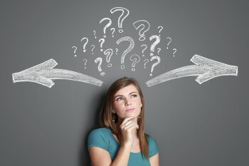 Mädchen vor Tafel, auf die zwei Pfeile in unterschiedliche Richtungen gemalt sind