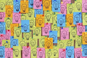 Tafel, die durch sehr viele bunte Post-Its mit Glühbirnen drauf, nicht mehr sichtbar ist